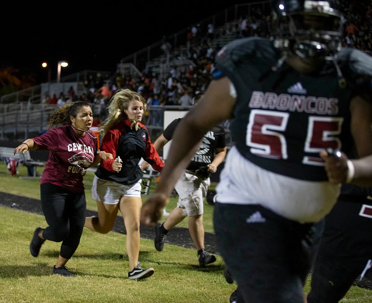 طلاب يركضون على ملعب كرة قدم جامعي أثناء احتفال عودة الخريجين وسط حشد، يعكس أجواء الفرح والتوتر في الجامعات السوداء التاريخية.