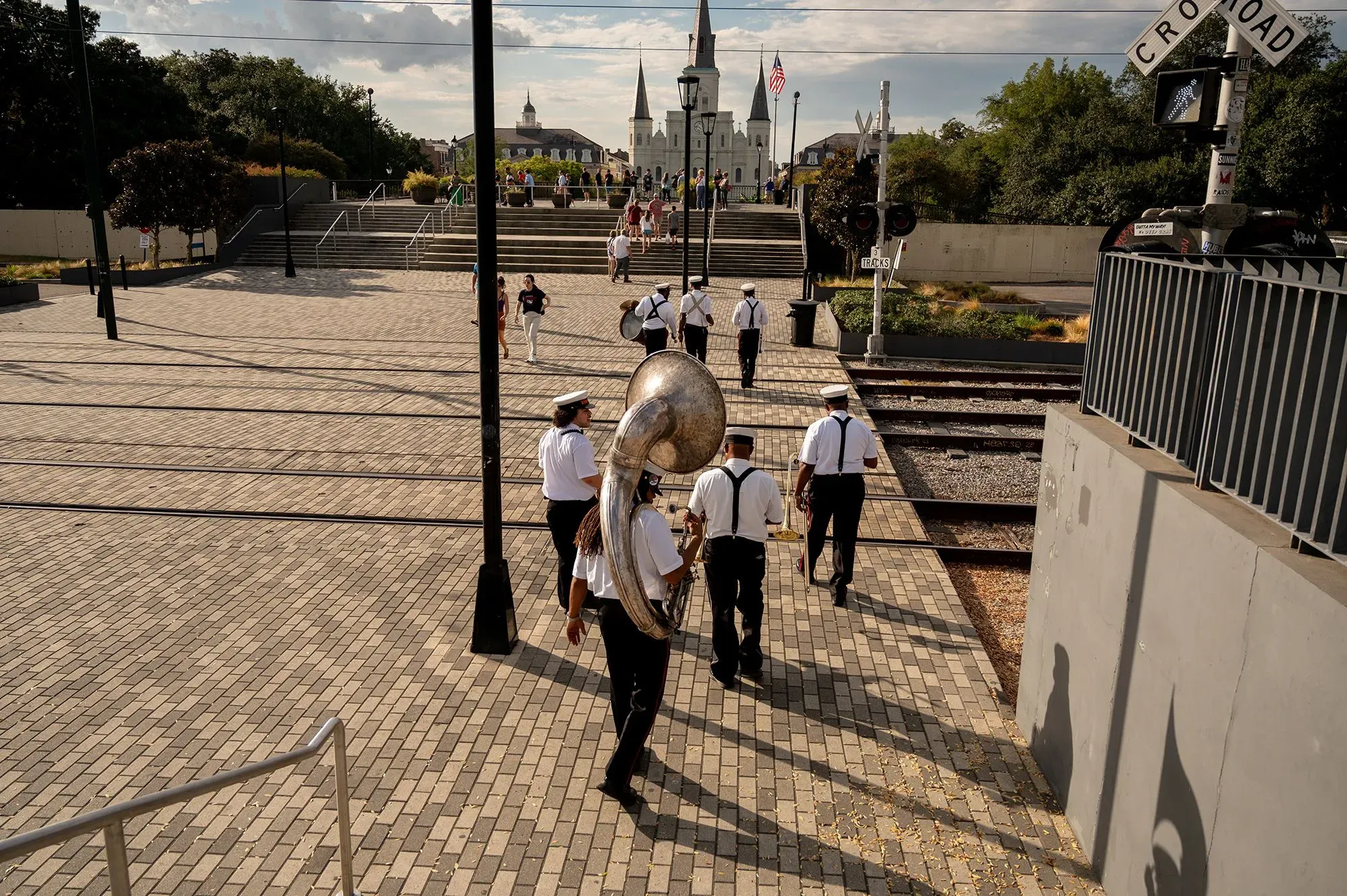 فرقة نحاسية تتجه نحو الشارع في نيو أورلينز، تحمل آلاتها وتحتفل بالثقافة المحلية، مع خلفية معالم المدينة.