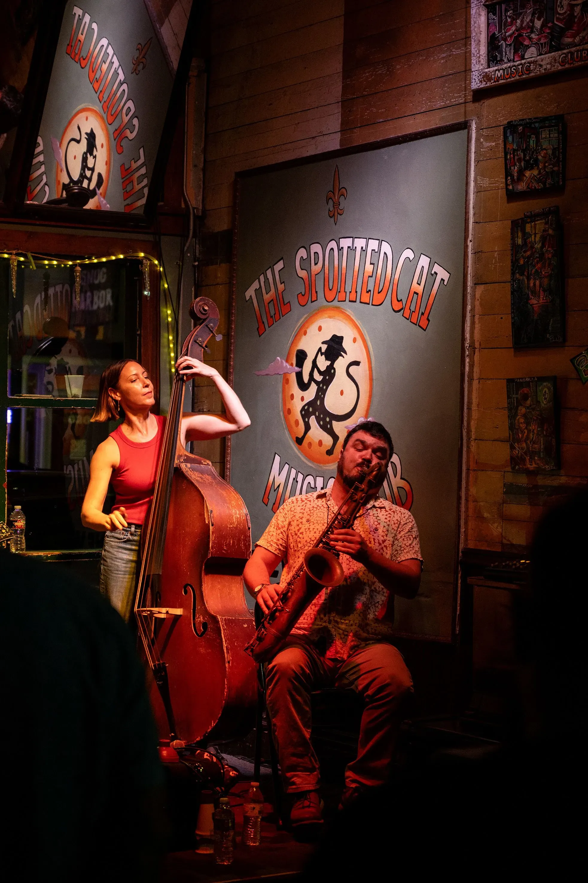 عازف ساكسفون وامرأة تعزف على آلة البيس في نادي "The Spotted Cat" في نيو أورلينز، يعكسان روح الموسيقى الحية في المدينة.
