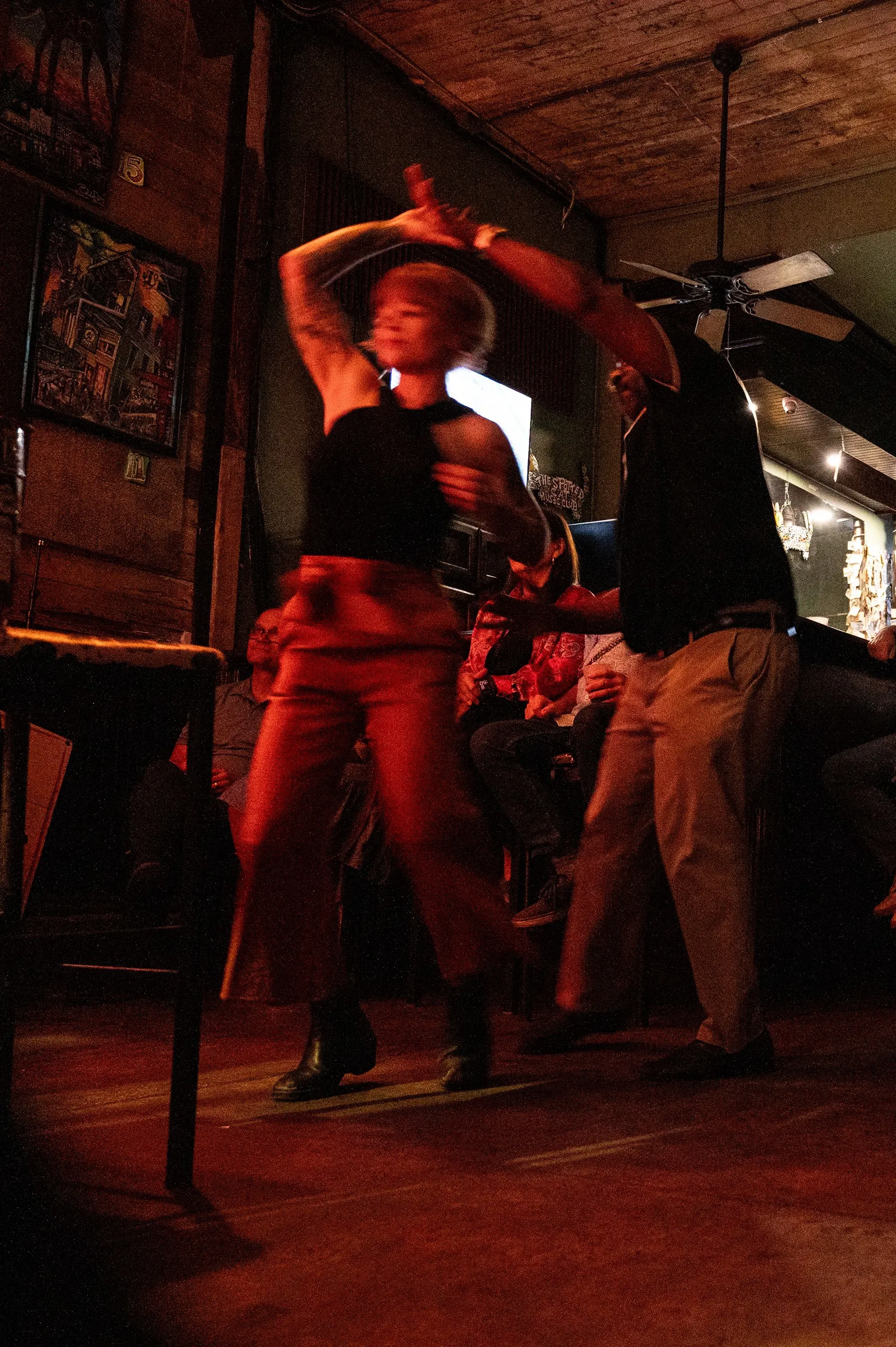 راقصتان تتبادلان الحركات في نادٍ اجتماعي بنيو أورلينز، مع جمهور خلفهما يستمتع بالأجواء الحماسية للموسيقى.