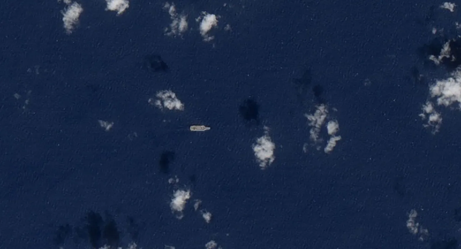 سفينة عسكرية صغيرة تظهر في مياه البحر الكاريبي، محاطة بغيوم، في سياق التوترات العسكرية بين فنزويلا والولايات المتحدة.