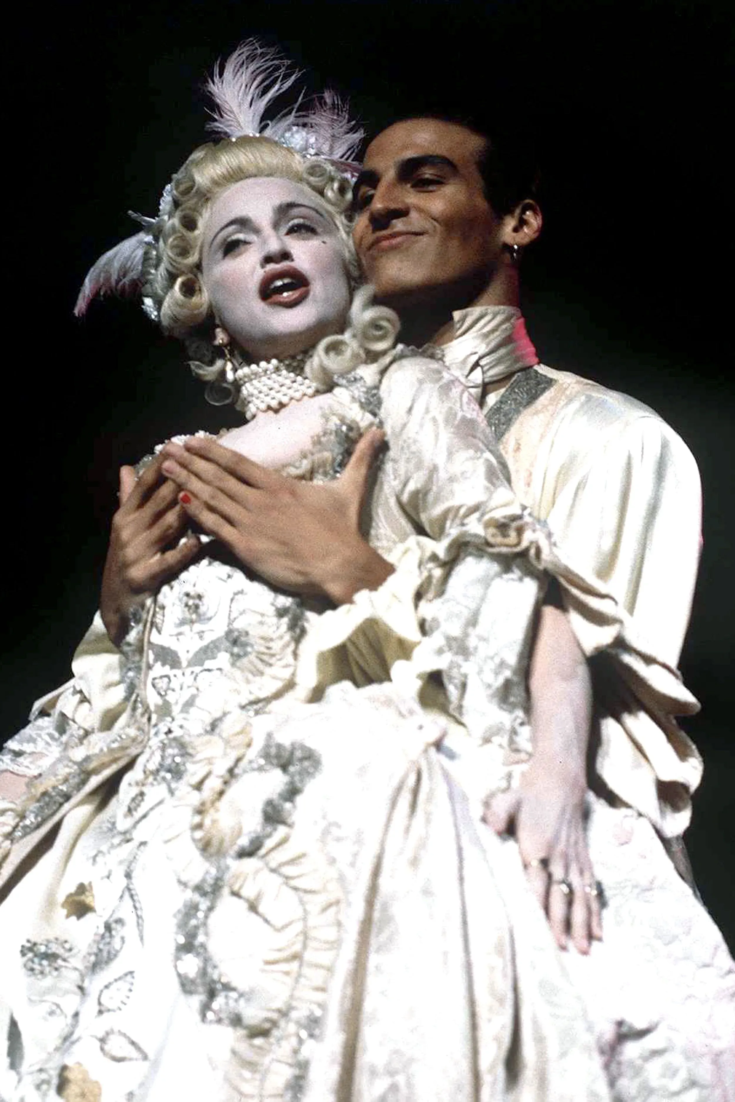 مشهد من عرض موسيقي يجسد ماري أنطوانيت، حيث يرتدي شخصان أزياء تاريخية فاخرة، مع تسريحات شعر متقنة، يعبران عن الفخامة والدراما.