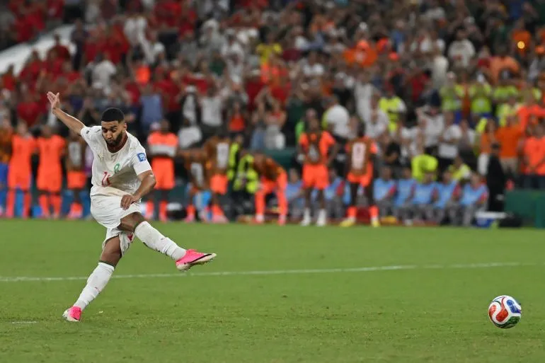 لاعب المنتخب المغربي يسدد الكرة بقوة في مباراة حاسمة ضمن بطولة كأس العالم FIFA 2026 وسط حضور جماهيري كبير.