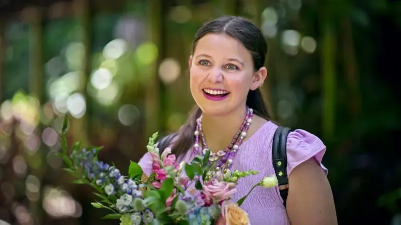 ماديسون ماريلا، مشاركة في برنامج "الحب في الطيف"، تبتسم حاملة باقة من الزهور، تعكس تجربتها في البحث عن الحب كفرد مصاب بالتوحد.