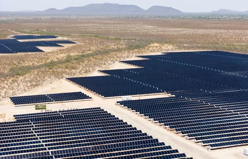 حقول شمسية شاسعة تحتوي على صفوف من الألواح الشمسية، تمتد عبر الأراضي القاحلة، مما يعكس التوجه نحو الطاقة المتجددة في الولايات المتحدة.
