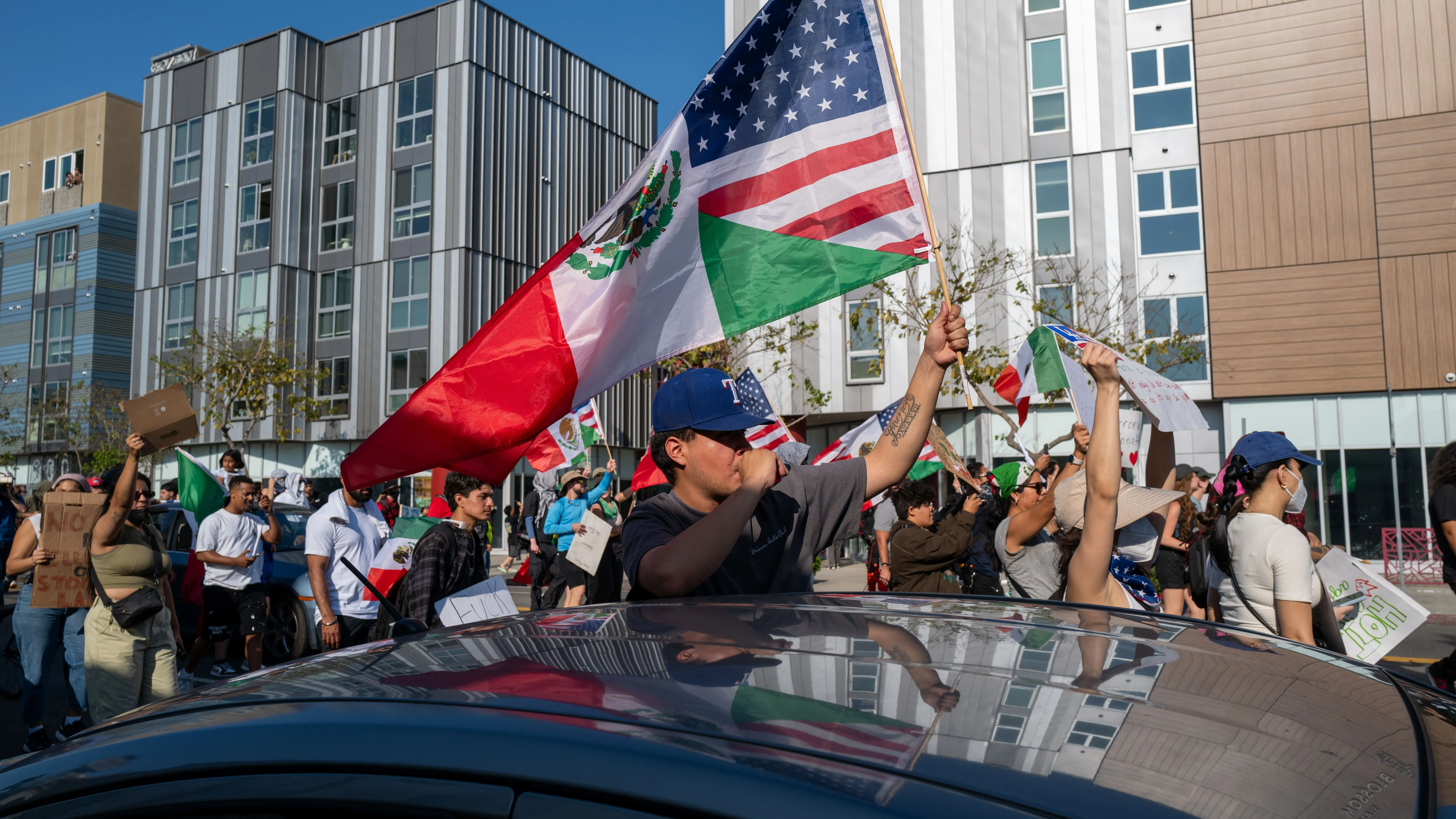 محتجون يحملون أعلام الولايات المتحدة والمكسيك في مظاهرة ضد عمليات الترحيل، تعبيرًا عن معارضتهم لسياسات ترامب.