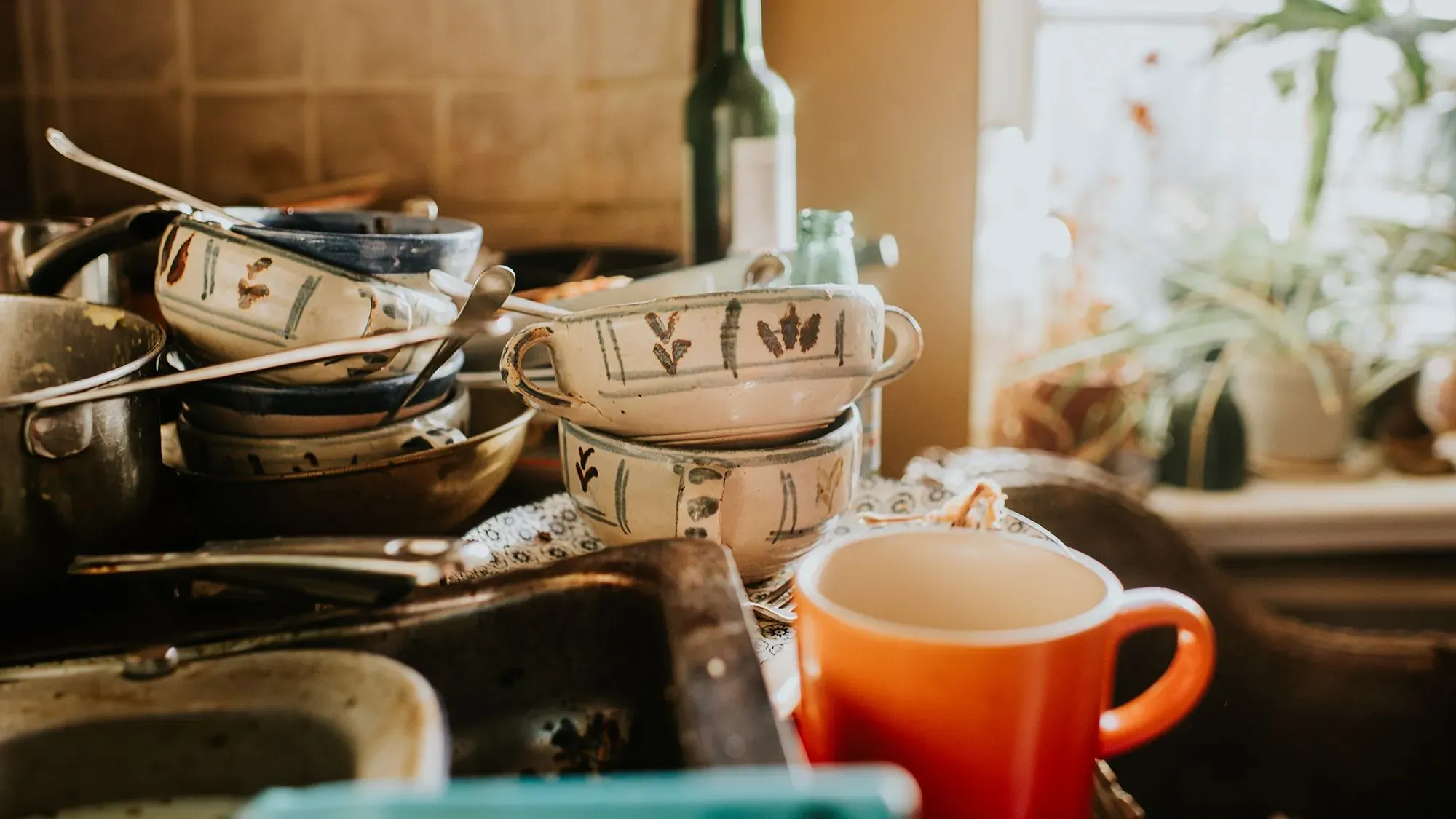 أطباق وأوعية متراكمة بشكل عشوائي في مطبخ فوضوي، مما يعكس ضغوط المماطلة والتحديات النفسية المرتبطة بها.