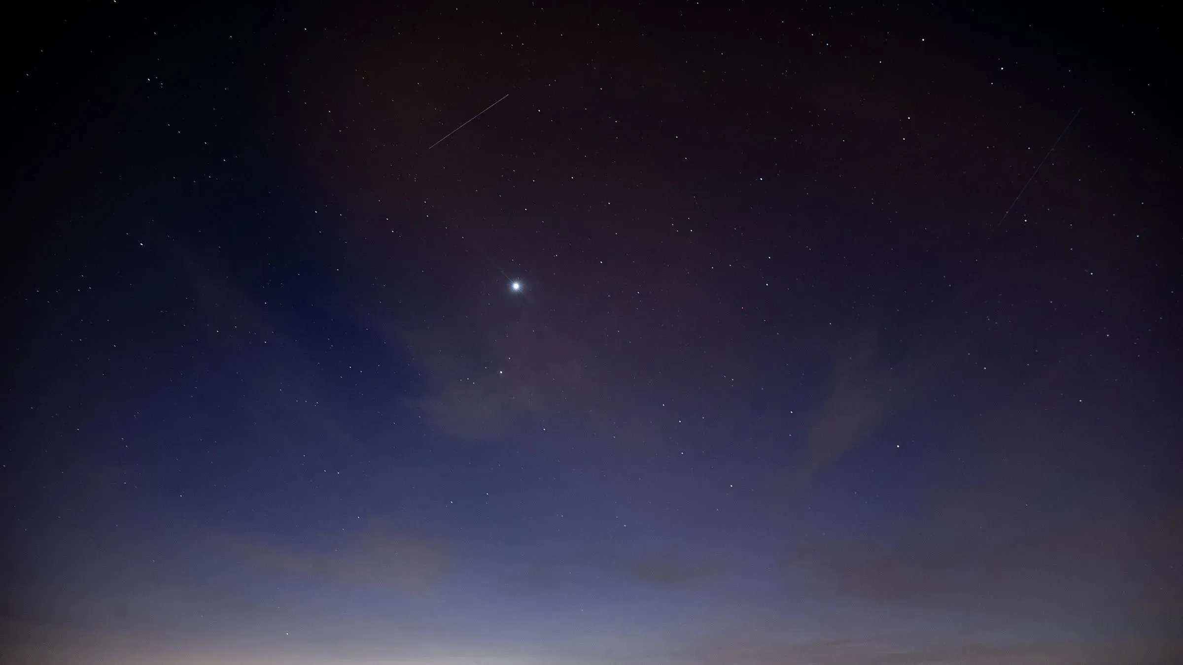 سماء الليل مليئة بالنجوم مع ظهور كوكب الزهرة اللامع، بينما تتواجد كواكب أخرى مثل المريخ وزحل في الأفق الغربي.