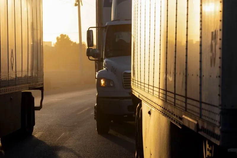 صورة لشاحنات نقل على طريق حدودي، تعكس حالة عدم اليقين في التجارة نتيجة التهديدات بفرض تعريفات جمركية جديدة.