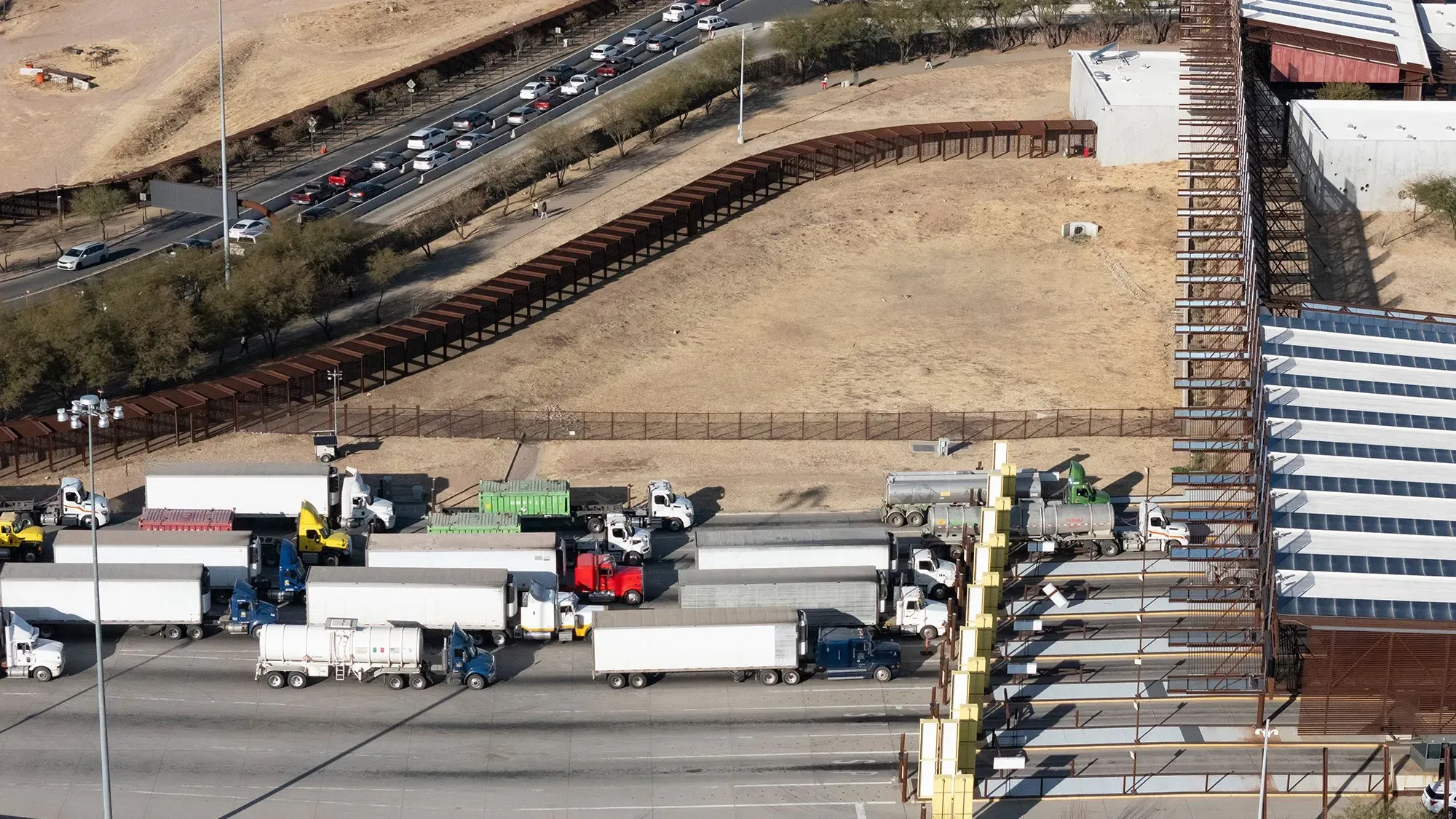 ازدحام مروري على الحدود الأمريكية المكسيكية، مع شاحنات تجارية تنتظر عبور الحدود، مما يعكس تأثير التعريفات الجمركية المحتملة.