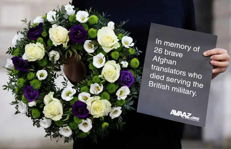 إكليل زهور يحمل رسالة تكريمية لـ 26 مترجماً أفغانياً شجاعاً توفوا أثناء خدمتهم في الجيش البريطاني، مع ألوان زاهية.