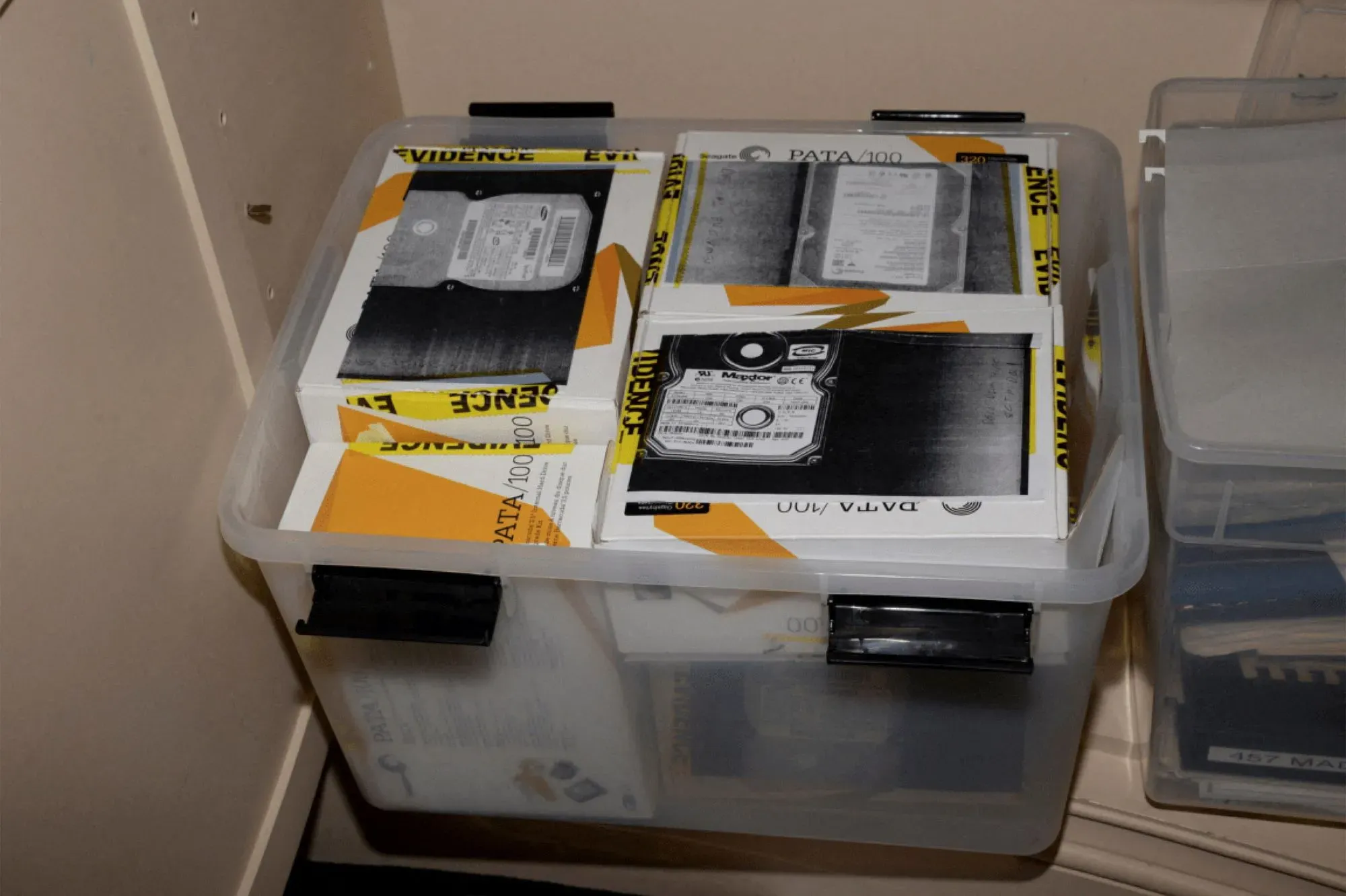 صندوق يحتوي على أقراص صلبة وملفات تتعلق بملفات جيفري إبستين، مع وجود علامات تشير إلى أنها أدلة.