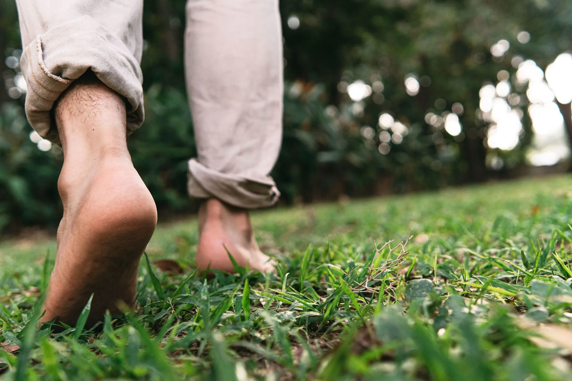 شخص يمشي حافي القدمين على العشب، مع التركيز على أهمية التأريض وفوائده الصحية، كما تم ذكره في المقال.