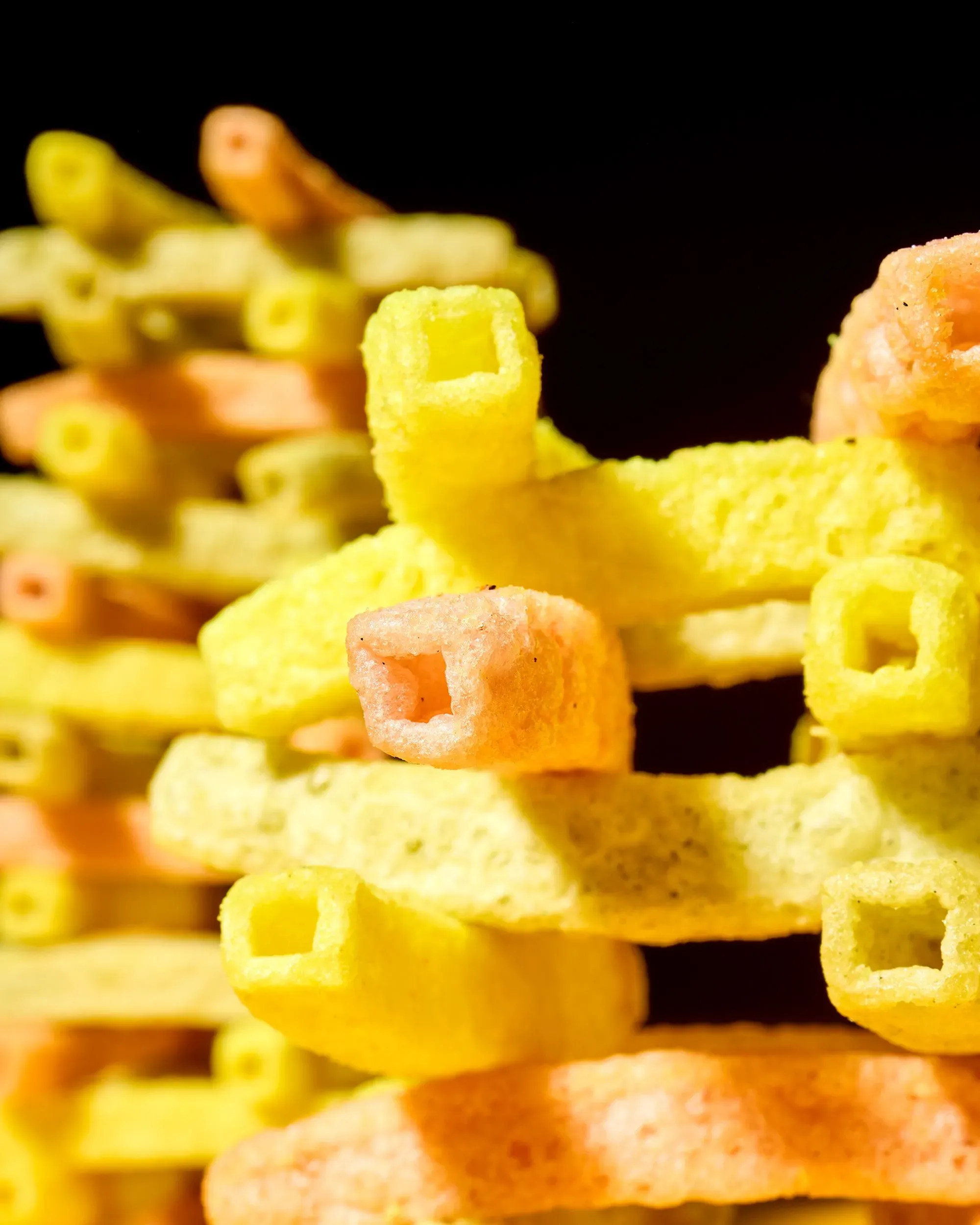 وجبات خفيفة ملونة مصنوعة من الحبوب، تُظهر مزيجًا من الأشكال والألوان، تعكس جاذبية الأطعمة فائقة المعالجة.