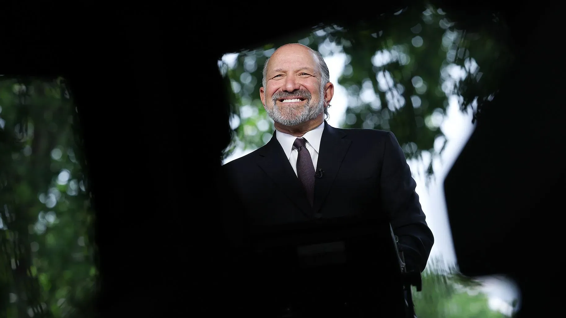 وزير التجارة هوارد لوتنيك مبتسم خلال مقابلة، مع خلفية طبيعية، يتحدث عن اتفاق التجارة بين الولايات المتحدة والصين.