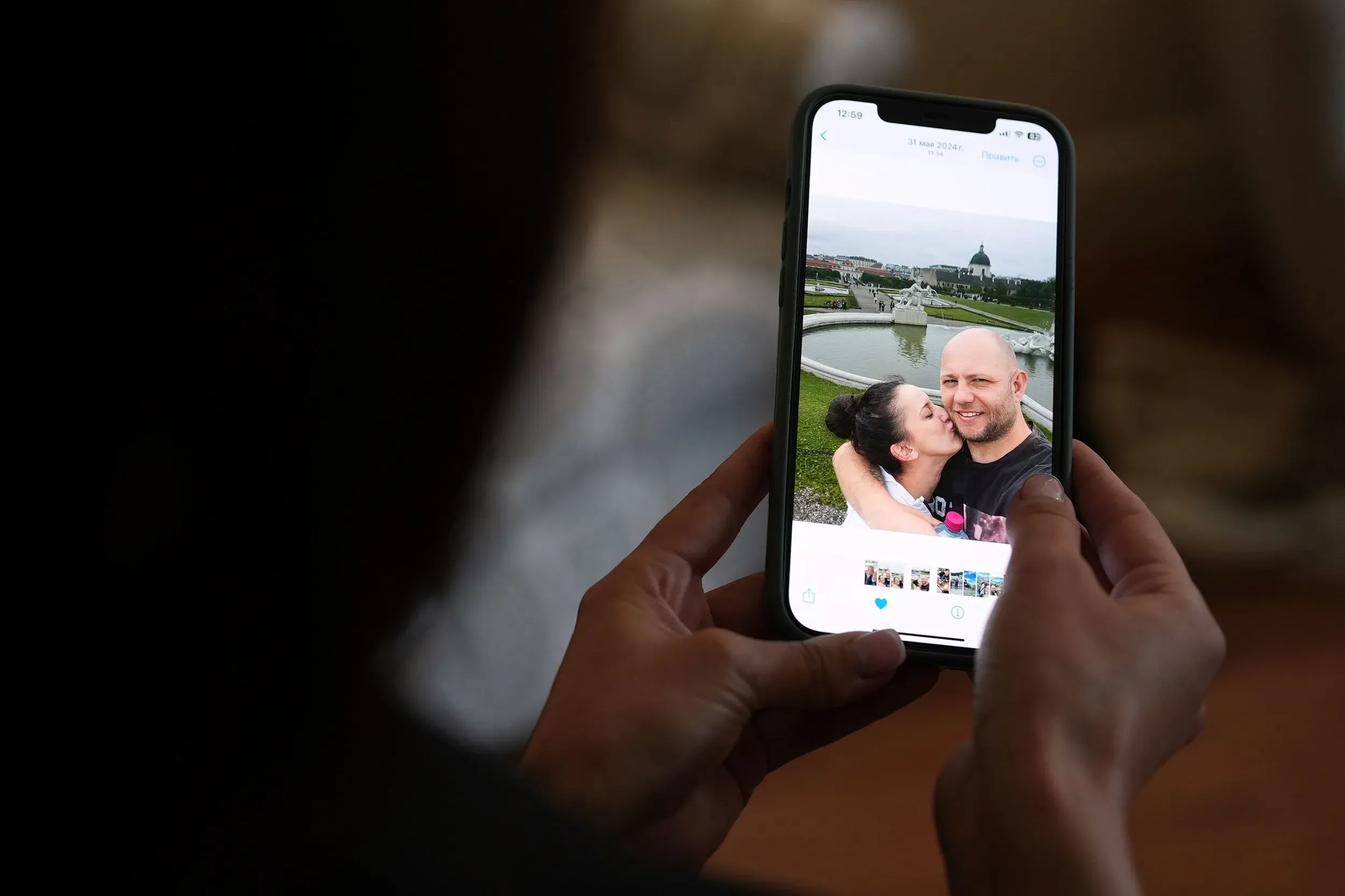 صورة لامرأة ورجل يبتسمان معًا في لقطة سيلفي، يظهران في مكان خارجي جميل مع خلفية طبيعية ومعمارية.