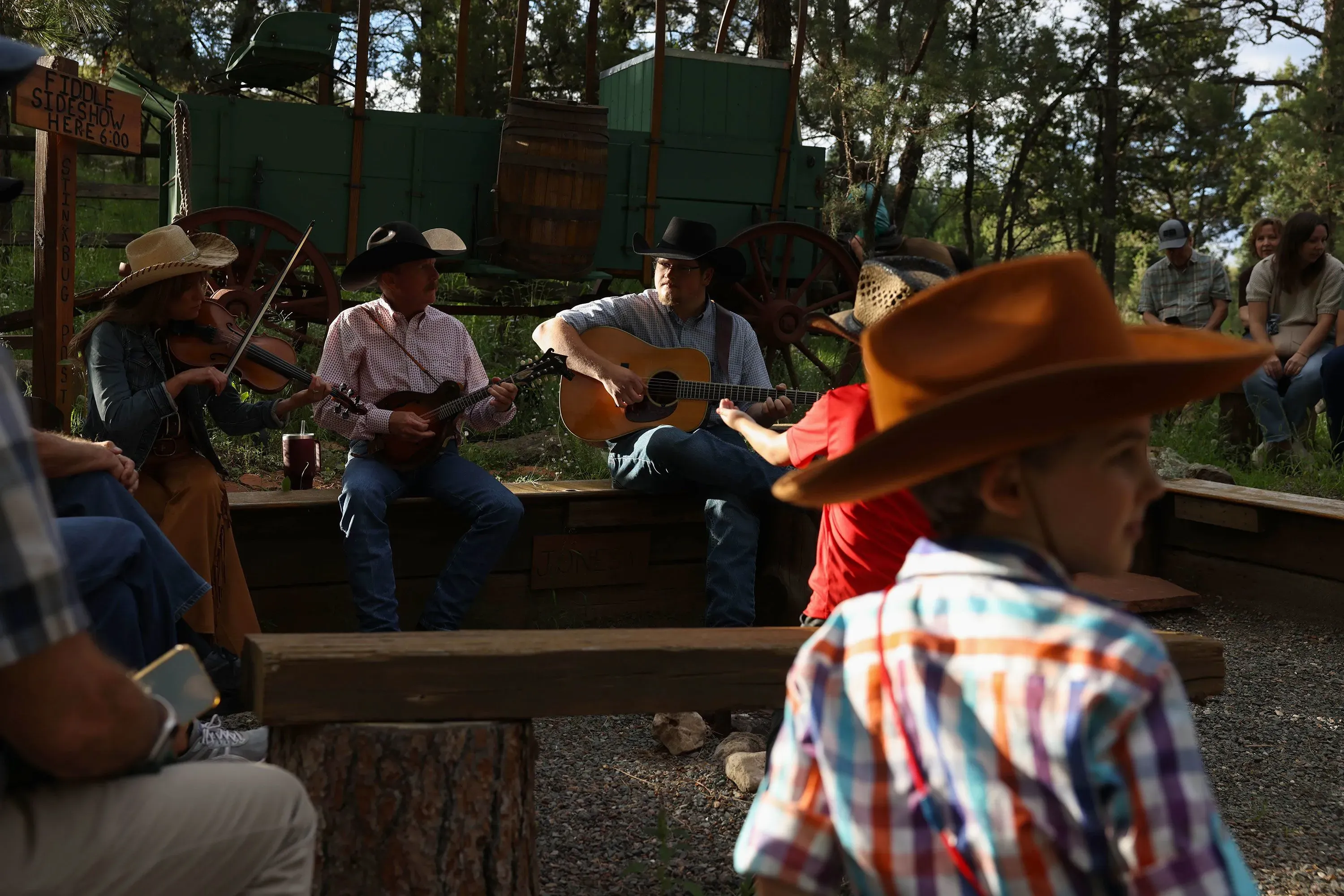 مجموعة من الموسيقيين يرتدون قبعات رعاة البقر يعزفون في الهواء الطلق، بينما يجلس الجمهور حولهم في أجواء احتفالية في رويدوسو.