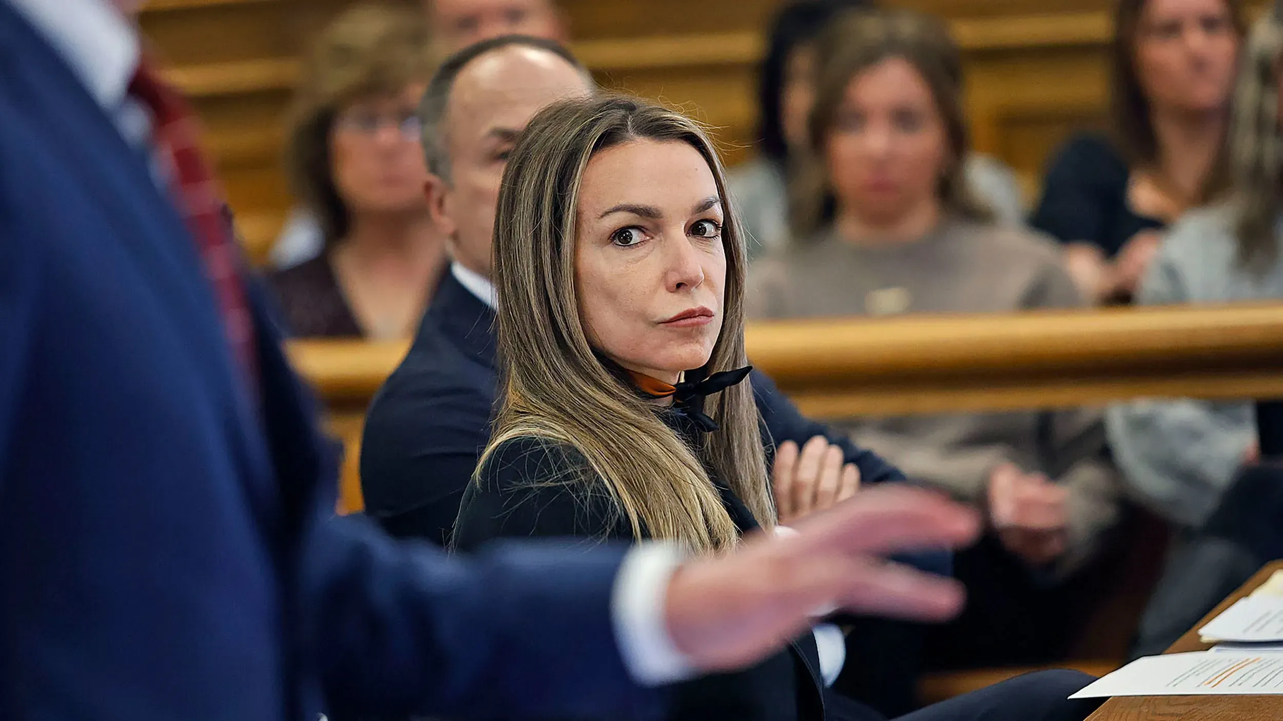 امرأة تجلس في قاعة المحكمة خلال محاكمة قتل مثيرة للجدل، محاطة بمحاميها ومشاهدين، في ظل توتر شديد بشأن القضية.