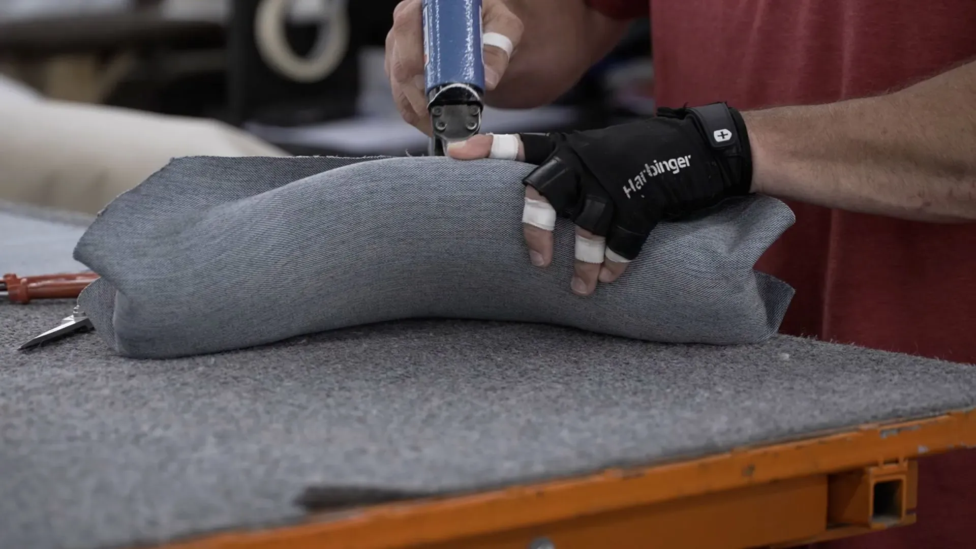 يد تظهر يدًا عاملة ترتدي قفازًا، وهي تستخدم أداة لتنجيد قطعة من الأثاث في مصنع. تعكس الصورة الجهود المبذولة لإنعاش صناعة الأثاث في كارولينا الشمالية.