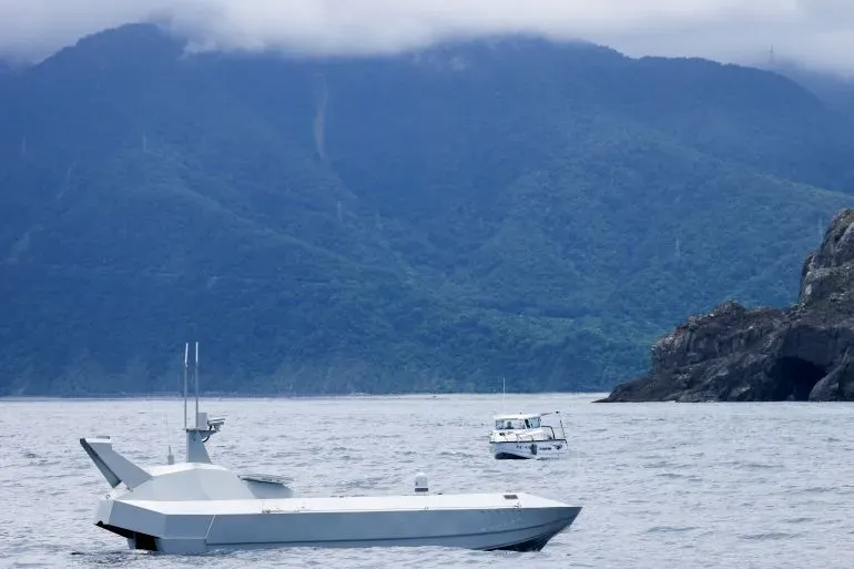 زورق بحري بدون طيار يبحر في خليج سواو بتايوان، مع خلفية جبلية، في إطار جهود تعزيز الدفاع البحري ضد التهديدات الصينية.