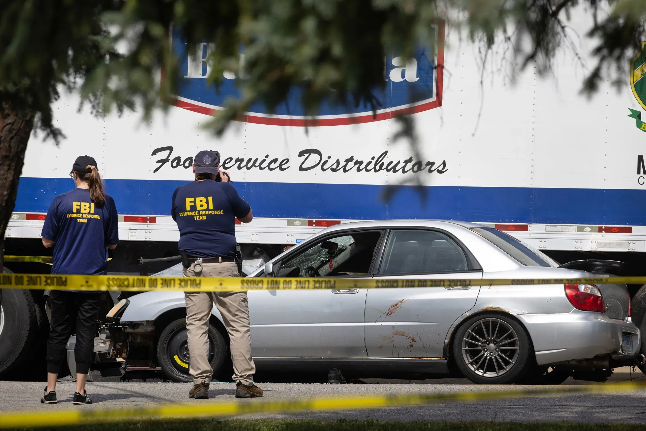 عملاء من مكتب التحقيقات الفيدرالي يفحصون موقع حادث حيث تم اتهام امرأة بصدم سيارة دورية. تظهر السيارة المتضررة خلف شريط الشرطة.
