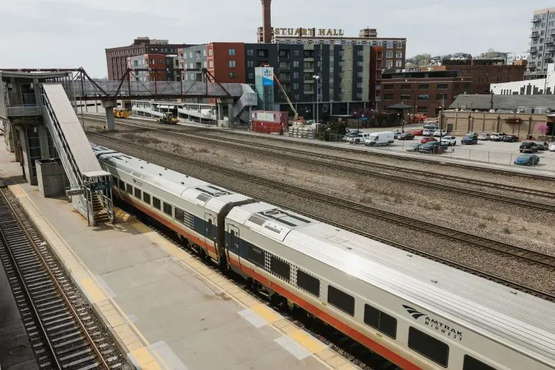 قطار متوقف في محطة في مدينة كانساس سيتي، مع مباني حضرية خلفه، مما يعكس التحديات الاقتصادية وتأثير تسريح العمال الفيدراليين.