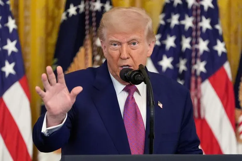 ترامب يتحدث خلال حفل توقيع قرارات تتعلق بمعايير السيارات الكهربائية، مع أعلام الولايات المتحدة خلفه، معبرًا عن آرائه حول السياسات البيئية.