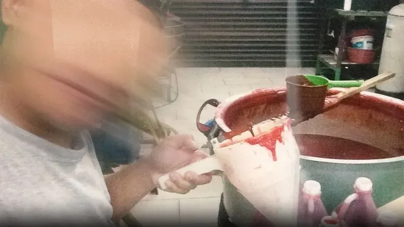 شخص يحمل قمعًا ويقوم بصب سائل أحمر في وعاء كبير، مع خلفية تظهر أدوات مطبخية، تعكس ظروف العمل في مطاعم تديرها شركة GISBH.