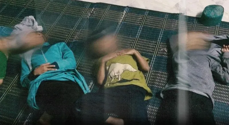 أطفال مستلقون على الأرض في مركز رعاية، يعانون من سوء التغذية والاستغلال، بعد إنقاذهم من مداهمات الشرطة الماليزية.