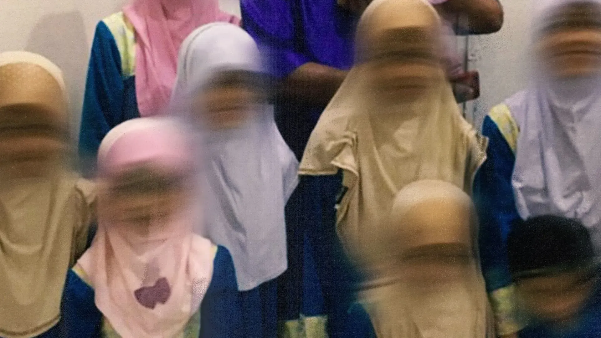 مجموعة من الأطفال يرتدون ملابس تقليدية، يظهرون في صورة غير واضحة، بعد إنقاذهم من دور رعاية تديرها شركة GISBH في ماليزيا.