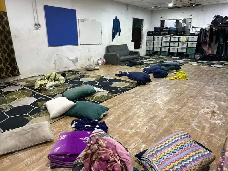 غرفة فارغة مع وسائد مبعثرة وأثاث بسيط، تُظهر آثار الإهمال، في سياق مداهمات للشرطة في دور رعاية تابعة لشركة GISBH.