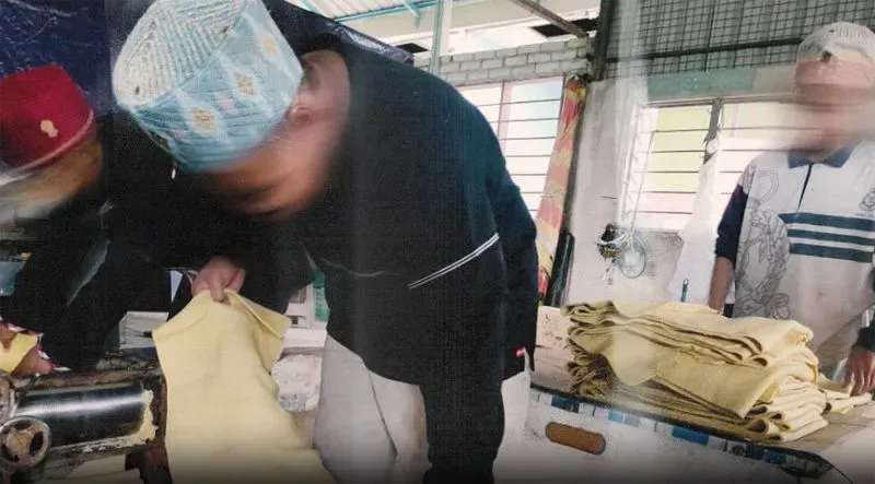 عمال في مصنع تابع لشركة GISBH، يظهرون وهم يعملون على تجهيز المواد، وسط ظروف غير واضحة تشير إلى استغلالهم.