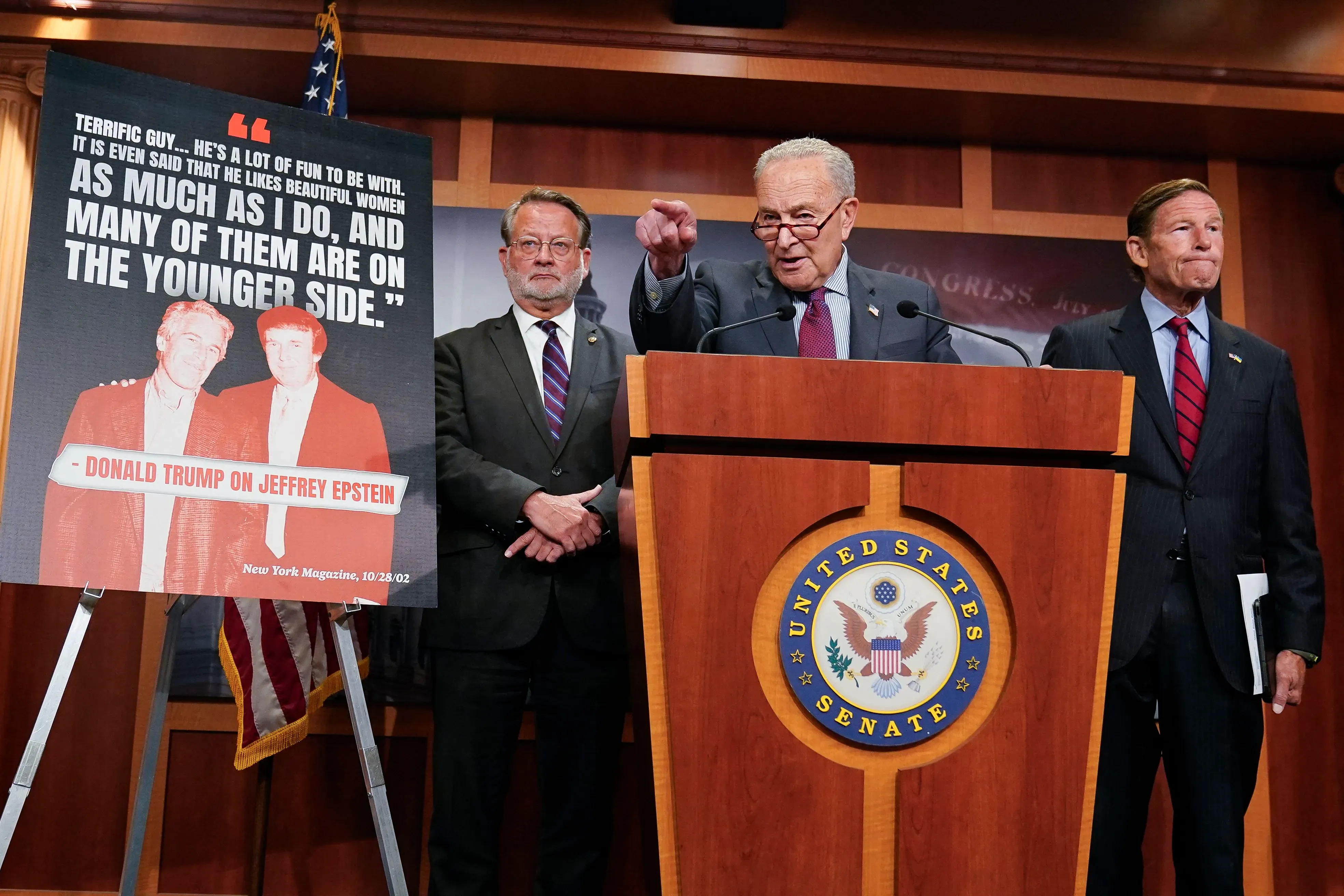 مؤتمر صحفي في مجلس الشيوخ، حيث يتحدث تشاك شومر عن تصريحات سابقة لدونالد ترامب حول جيفري إبشتاين، مع وجود صورة خلفه.