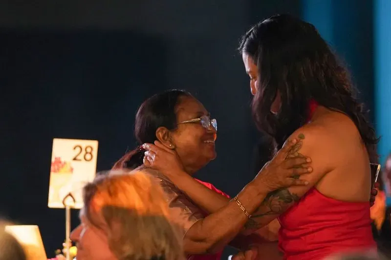 احتفال مؤثر بين امرأتين، إحداهما ترتدي فستانًا أحمر، تعبر عن الفرح بعد فوز بانو مشتاق وديبا بهاسثي بجائزة البوكر الدولية.