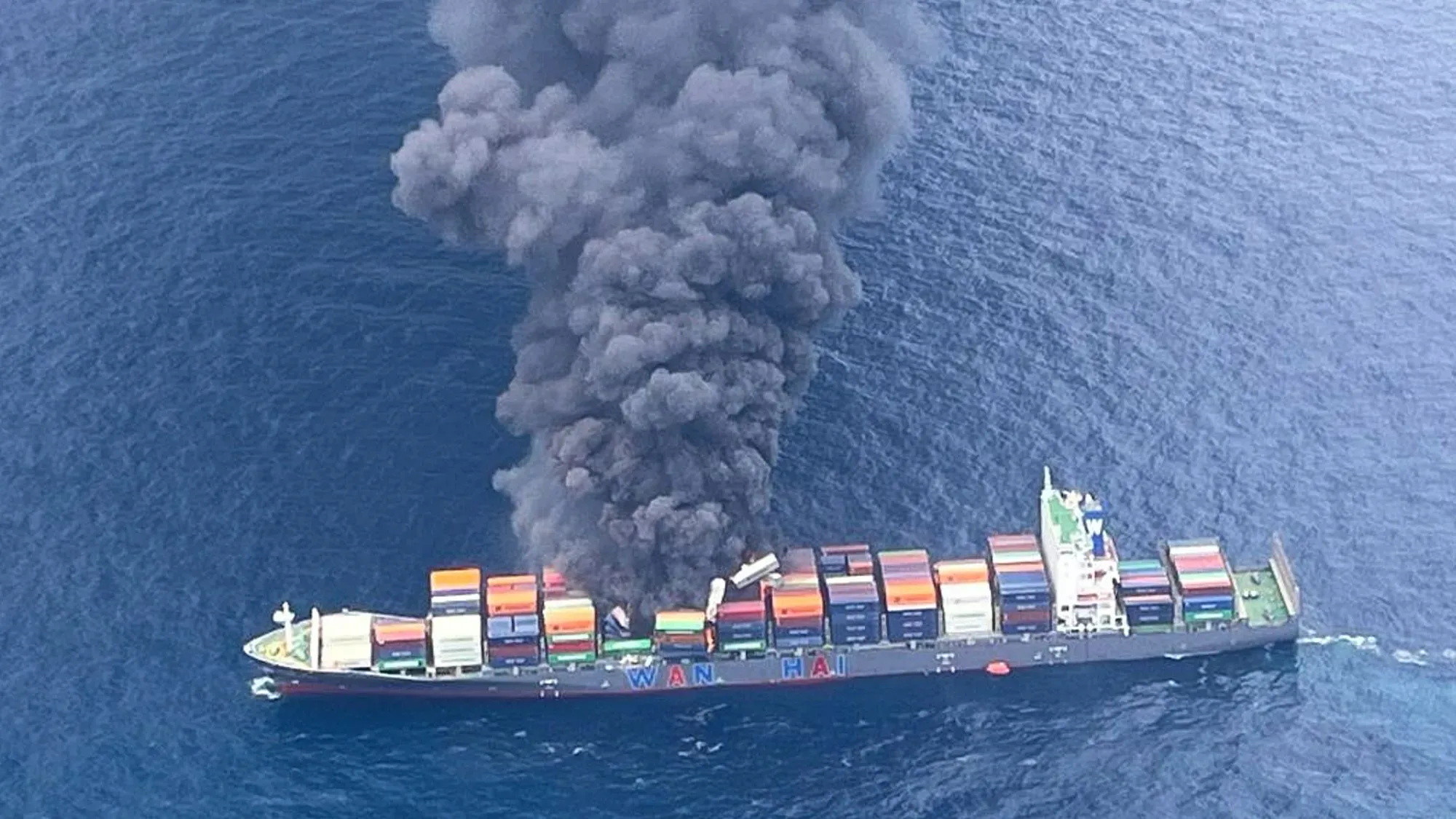 سفينة الحاويات إم في وان هاي 503 تشتعل فيها النيران قبالة ساحل كيرالا، مع تصاعد دخان أسود كثيف نتيجة الانفجارات.