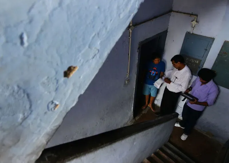 مشهد من داخل مبنى حيث يقوم موظف بإجراء إحصاء سكاني مع شخصين، في سياق مناقشة حول الطبقات الاجتماعية في الهند.