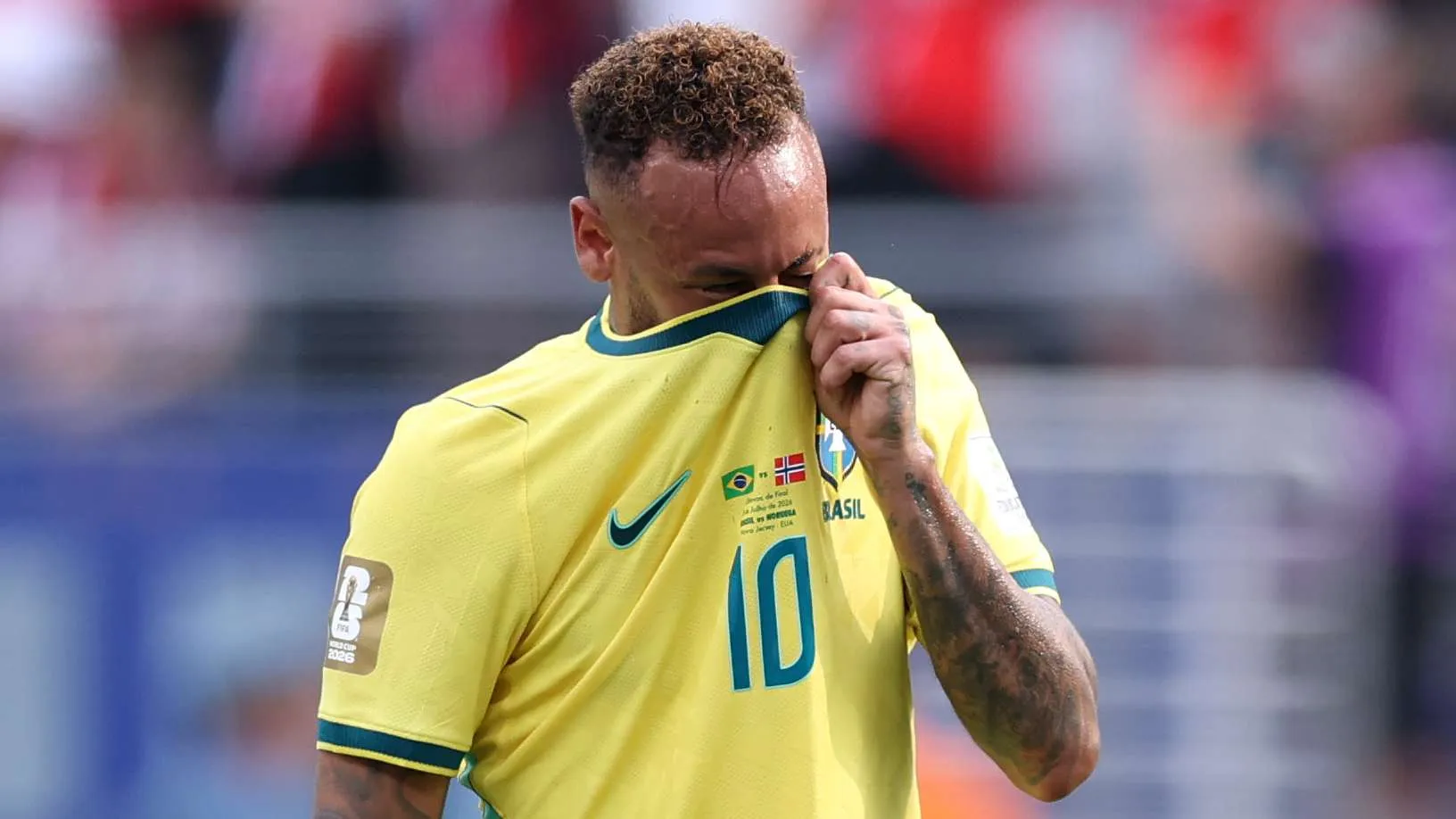 نيمار يرتدي قميص البرازيل رقم 10 ويغطي وجهه بالحزن بعد خروج المنتخب من كأس العالم 2022.
