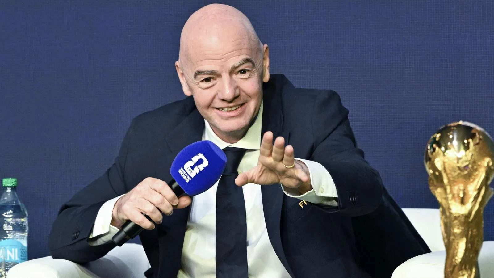 جياني إنفانتينو رئيس FIFA يتحدث في مؤتمر صحفي مع كأس العالم بجانبه، معبرًا عن تقديره لدور وائل جمعة في نجاح مونديال 2026.