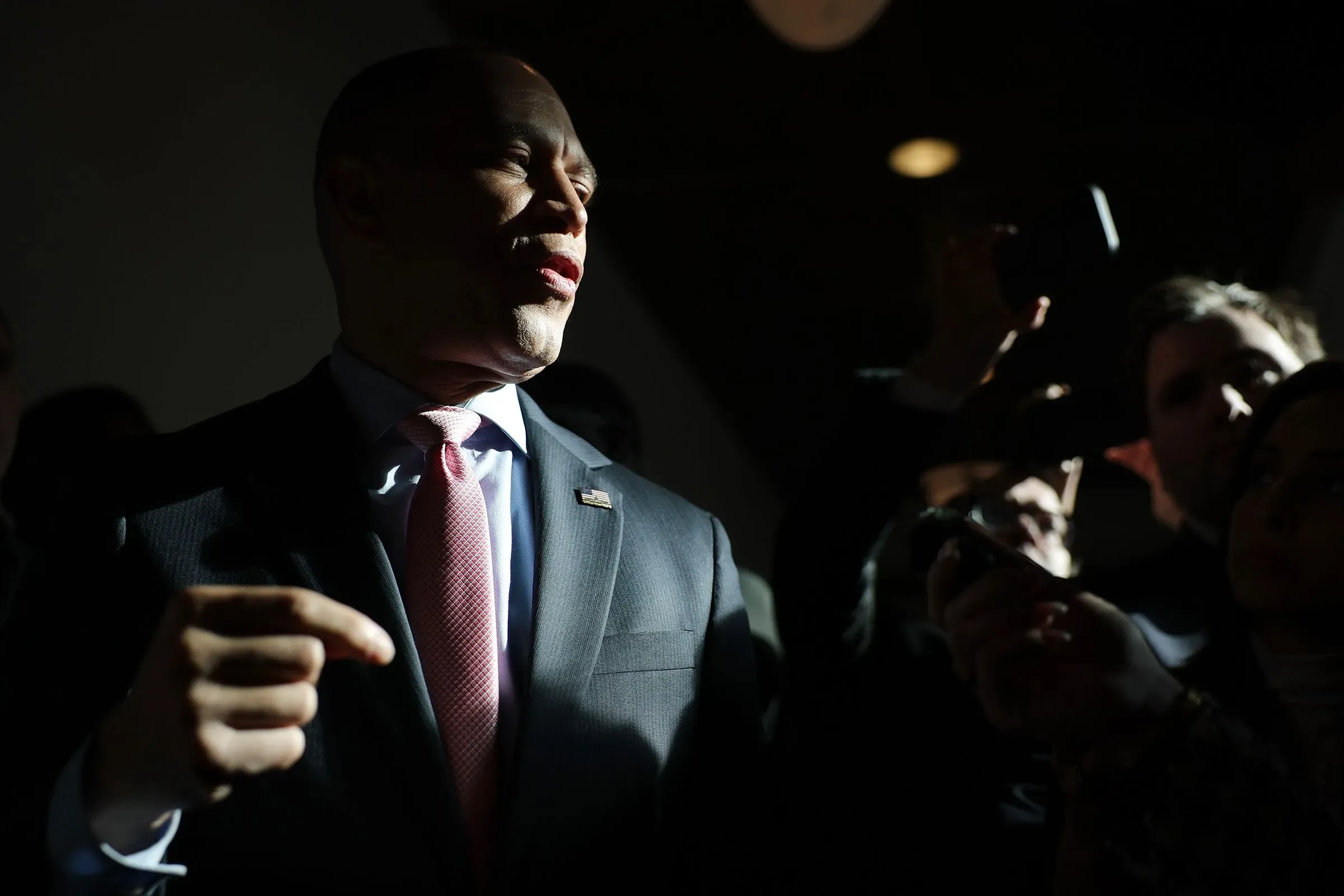 صورة لزعيم الأقلية الديمقراطية حكيم جيفريز يتحدث وسط مجموعة من الصحفيين، مما يعكس التوترات داخل الحزب حول عزل ترامب.