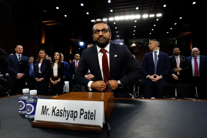 كاش باتيل، مدير مكتب التحقيقات الفيدرالي الجديد، يجلس أمام طاولة خلال جلسة استماع، محاطًا بعدد من الحضور خلفه.