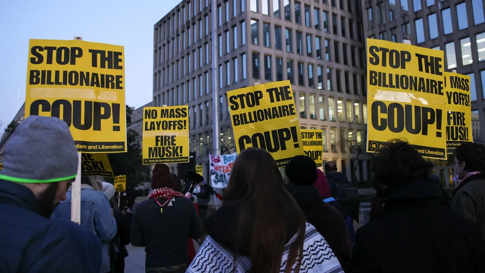 محتجون يحملون لافتات صفراء تطالب بوقف التخفيضات الحكومية والإقالات الجماعية، مع التركيز على ضرورة حماية العمال الفيدراليين.