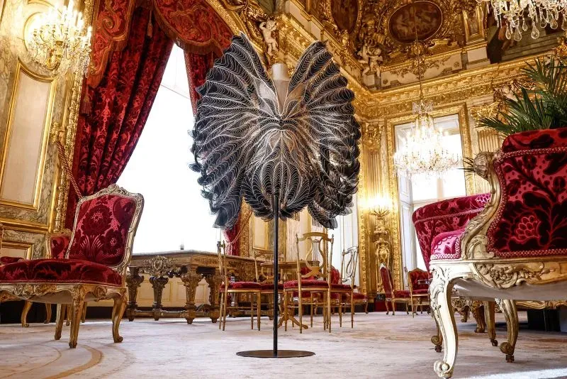 فستان يعكس تداخل الفن والموضة، مستعرضًا تفاصيل فنية مبتكرة في قاعة فاخرة بمتحف اللوفر.