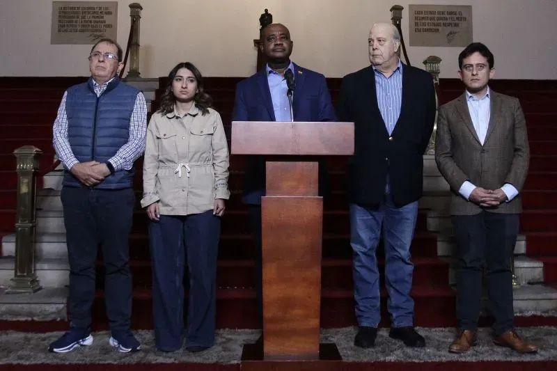 مؤتمر صحفي لعدد من المسؤولين أمام منصة يتحدثون عن قضية الترحيل، مع وجود درج في الخلفية وشخصيات بارزة.