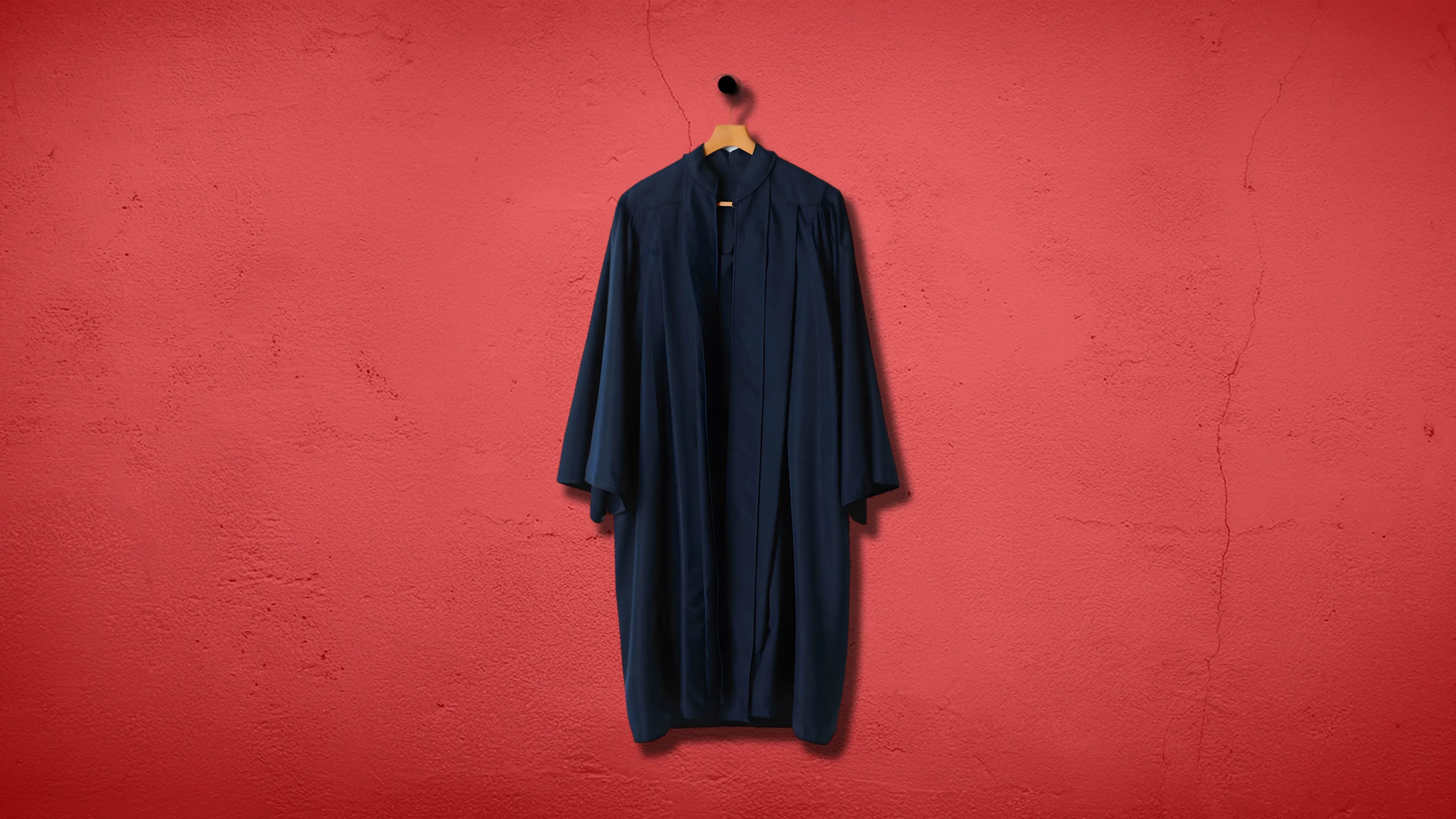 عباءة قاضي هجرة معلقة على شماعة أمام جدار أحمر، تعكس التحديات التي تواجه محاكم الهجرة في ظل التغيرات السياسية.