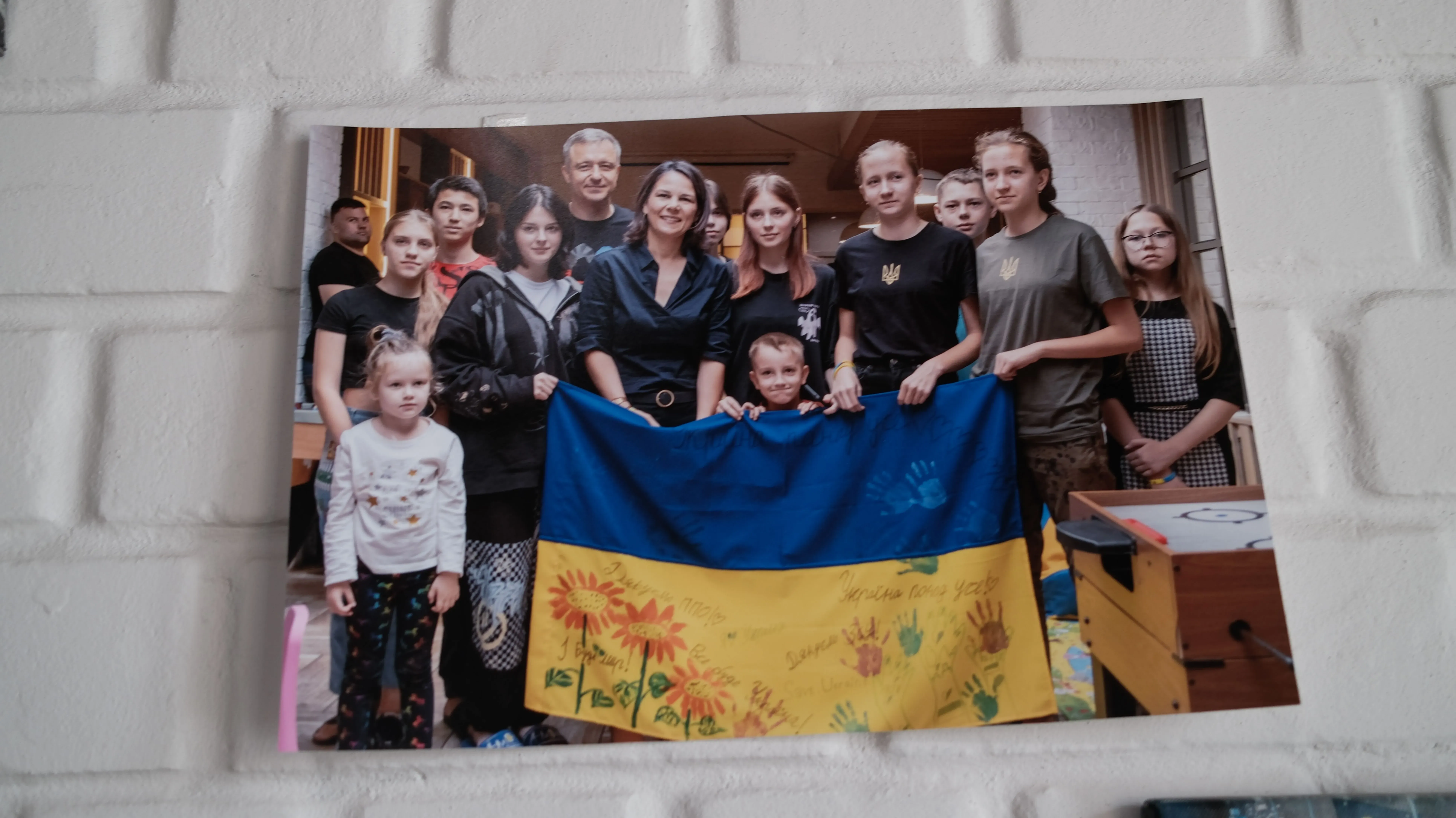 مجموعة من الأطفال والمراهقين الأوكرانيين يحملون علم أوكرانيا، مع وجود متطوعين من منظمة "أنقذوا أوكرانيا" في الخلفية، بعد عودتهم من روسيا.