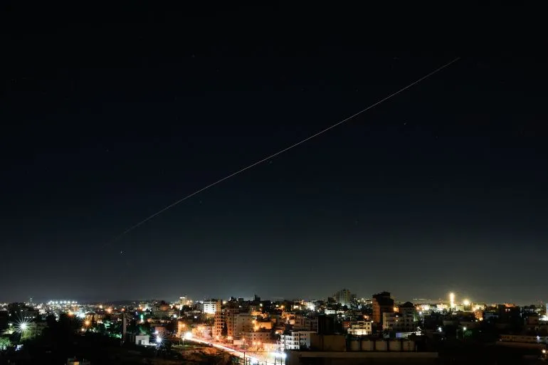 صور تظهر صواريخ تطلق في السماء فوق مدينة خلال الليل، تعكس تصعيد التوترات بين إسرائيل وإيران بعد تبادل الضربات.
