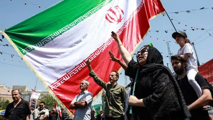 مواطنون إيرانيون يرفعون علم إيران خلال تجمع يعبر عن دعمهم لمواقف بلادهم في ملف مضيق هرمز وسط توترات إقليمية ومفاوضات مع عُمان.