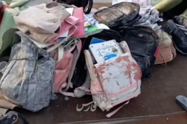 حقائب مدرسية مكدسة مع أوراق وكتب مدمرة، تعكس آثار الهجوم على مدرسة البنات في ميناب، حيث قُتل 165 تلميذة وموظفة.