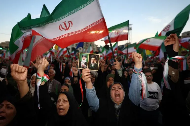 حشود من المتظاهرين الإيرانيين يحملون الأعلام الوطنية وصور القادة، معبرين عن دعمهم في سياق التوترات الإقليمية المتصاعدة.