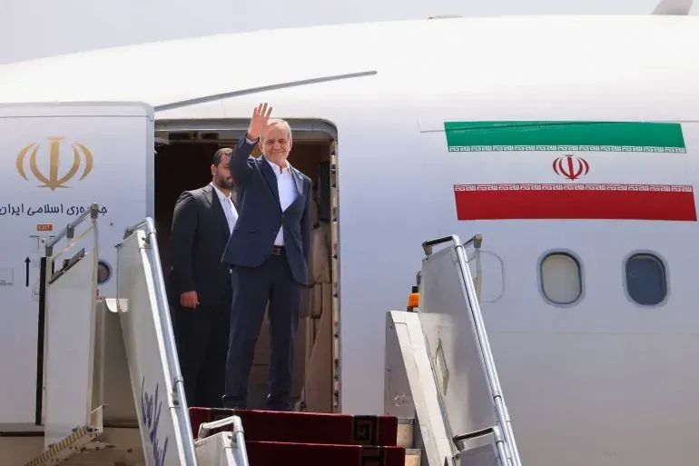 الرئيس الإيراني مسعود بيزشكيان يلوح بيده أثناء مغادرته الطائرة في زيارة لأرمينيا لمناقشة ممر زانغيزور المقترح.